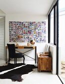 Console table and black-upholstered chair below photo collage on wall