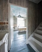 Blick von weißem Treppenaufgang durch offene Tür auf Wohnbad mit freistehender Badewanne
