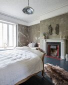 Sleigh bed in country-house bedroom with vintage patinated walls