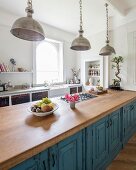 Vintage-Metallpendelleuchten über freistehender Küchenzeile mit blauen, patinierten Landhaus-Fronten und Küchenarbeitsplatte aus Eichenholz