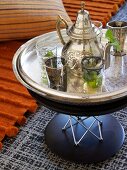 Silbertablett mit marokkanischer Teekanne und Gläsern auf modernem Beistelltisch