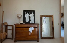 Picture of camisoles on top of antique chest of drawers next to floor-standing mirror