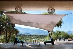 Terrace with wooden floor, awning, olive trees and modern plastic chairs