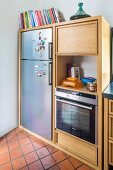 Pale wooden kitchen units with integrated fridge and oven
