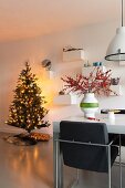 Brightly lit Christmas tree and upholstered chair in dining area in modern interior