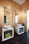 weiße Waschtischmöbel mit Waschschüsseln, Spiegel und Botschaft an apricotfarbener Wand