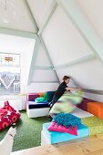 Colourful floor cushions below pastel ceiling beams of exposed roof structure