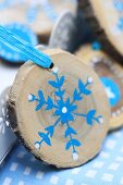 Small slice of tree trunk painted with blue and white snowflake as Christmas decoration