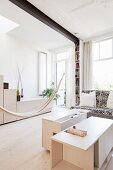 Hammock casually hung between custom furniture made from pale wood in bright interior