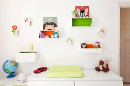 Changing mat on top of cabinet below toys in wooden crates hung on white wall