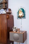 Skull on retro audio system below illuminated icon of Madonna and child on wall