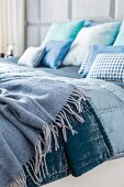 Doppelbett mit Decken und Kissen in Blautönen