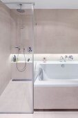 Walk-in shower with glass partition wall next to bathtub; continuous shelf in niche with indirect lighting