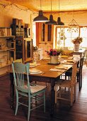 Set dining table, wooden chairs and row of vintage pendant lamps in rustic kitchen