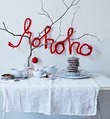 Festive buffet decorated with bare branch and crocheted wire lettering reading 'hohoho'