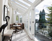 Antique table and chairs in bright, narrow conservatory