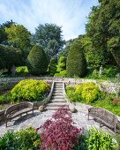 Benches, formal garden steps and topiary in elegant, summery park