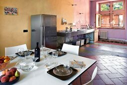 Open-plan, loft-apartment kitchen and modern, white dining area in old Castello decorated in complementary colours