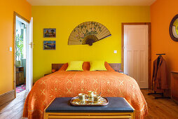 Fan on wall above bed in yellow and orange bedroom