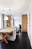 Hellgraue Polstersessel und klassische Schalenstuhl an langem Esstisch aus Massivholz in modernem Wohnraum