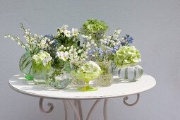 Arrangement of tiny vases of spring flowers on table