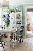 Various chairs around bouquet on wooden table and display case next to open door in rustic dining room