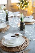 Christmas table festively set with raffia place mats, white crockery and hyacinths