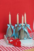 Candle holders made from bottles filled with sand and decorated with ribbons & decorative numbers