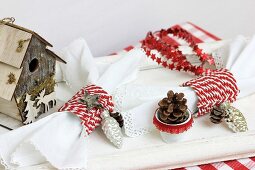 Weihnachtliche Tischdekoration mit Vogelhäuschen, Serviettenringen, Sternengirlande & Kiefernzapfen