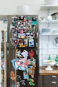 Fotosammlung an Edelstahl Kühlschrank mit Magneten angeheftet, neben Küchenzeile und Wandboard