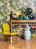 Yellow designer armchair and Chinese ornaments on console table against patterned wallpaper