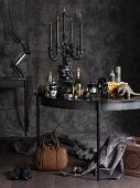 Gothic still-life arrangement with candelabra on table against charcoal-grey background