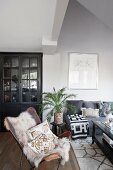 Ethnic accessories, black glass-fronted cabinet and sheepskin on leather armchair in living room