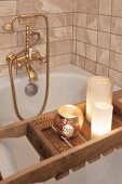 Vintage-style brass tap fittings and candles on bath caddy