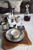 Place setting with silver bowl on rustic wooden board and carafe of red wine