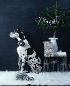 Dog with Christmas tree bauble hanging from collar sitting in room decorated in black and white