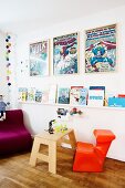 Wandboard mit Kinderbüchern, gerahmte Comic-Poster und poppig orangefarbenem Kinderstuhl, skandinavisches Flair