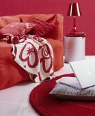 Hussensofa mit kuscheligen Kissen und Plaid in rot-weißem Ambiente, Laptop auf grauem Kissen am Boden