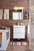 White washstand below mirrored cabinet in modern bathroom with rust-coloured tiles