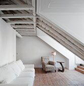 White sofa against wall and traditional armchair in background in converted attic with rustic ambiance
