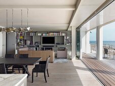 Offener Wohnraum mit Essplatz und Loungebereich vor offener Terrassentür mit Meerblick
