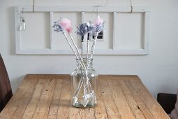 Hand-made arrows with coloured feather flights in retro glass jar on wooden table