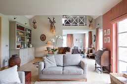Grey and pink colour scheme in open-plan interior with grey sofa next to French windows