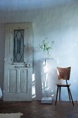 Vintage door leaning against wall, plant stand and retro wooden chair