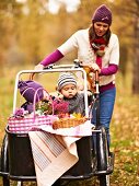 Mutter transportiert Kinder und Körbe fürs Herbstpicknick im Lastenfahrrad
