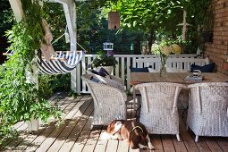Hammock and white wicker armchair on pleasant wooden veranda