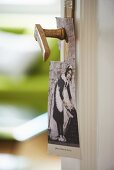 Nostalgisches Türschild mit Dienstmädchen-Motiv an antiken Türdrücker gehängt