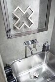 Edelstahl-Waschbecken vor Wandarmatur und Spiegel mit verchromtem Rahmen