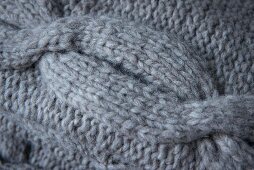 A knitted cable pattern made from grey mixed yarn (close)