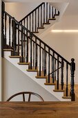 Elegant, restored wooden staircase with black-painted bannisters and indirect lighting